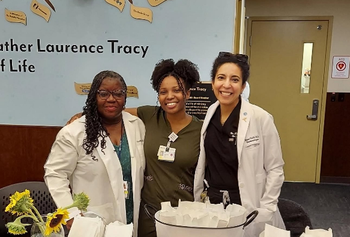 Student stands between two physicians in white coats, all smiling