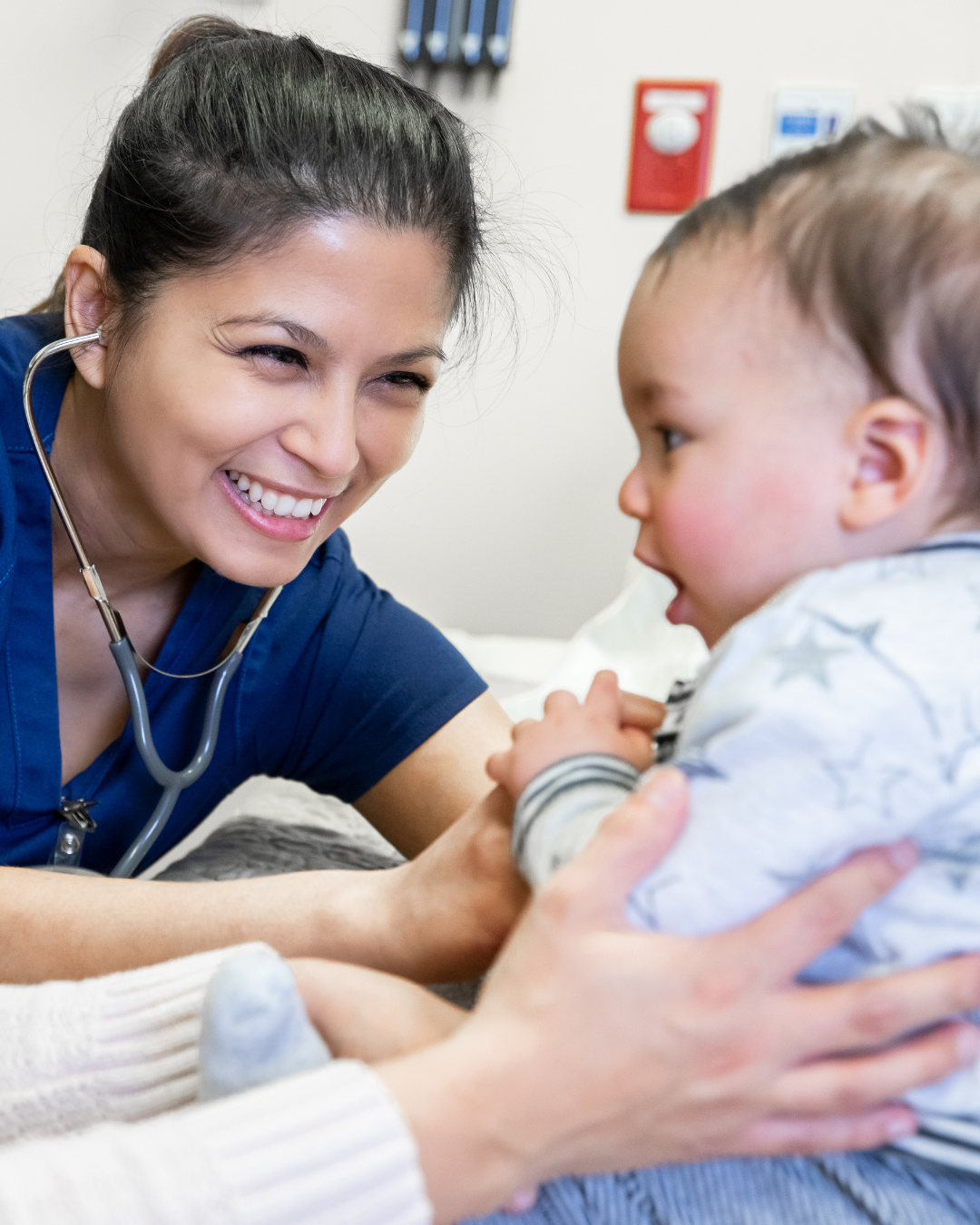 Physician Assistant (PA) smiles at baby - a pediatric patient.