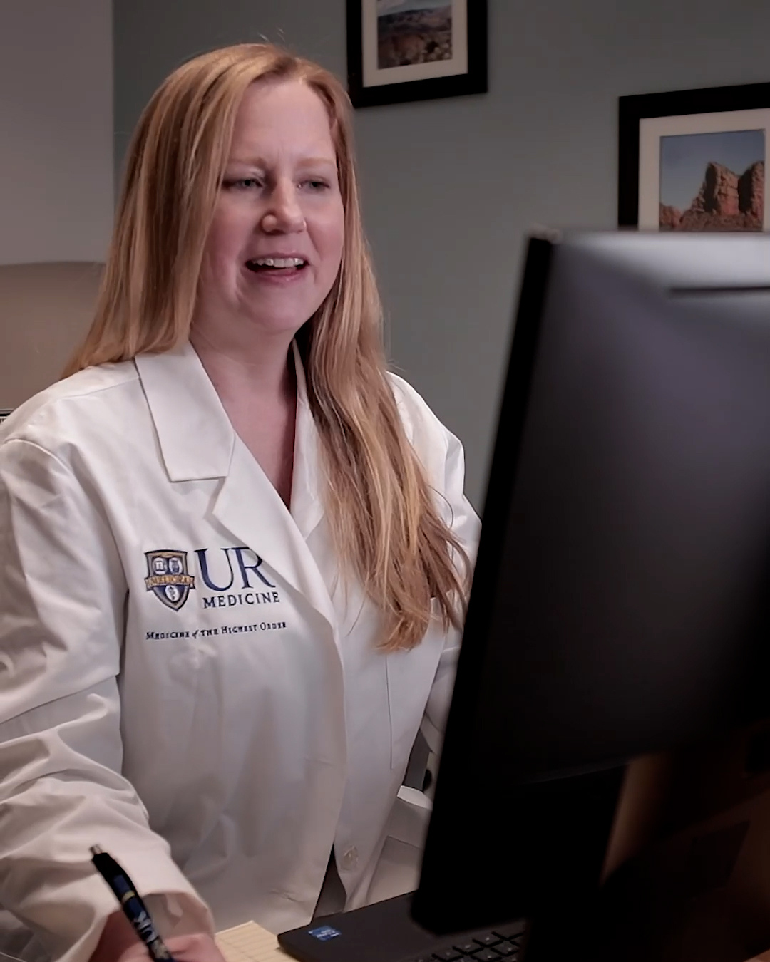 Nurse practitioner looks at computer for virtual urgent care visit.