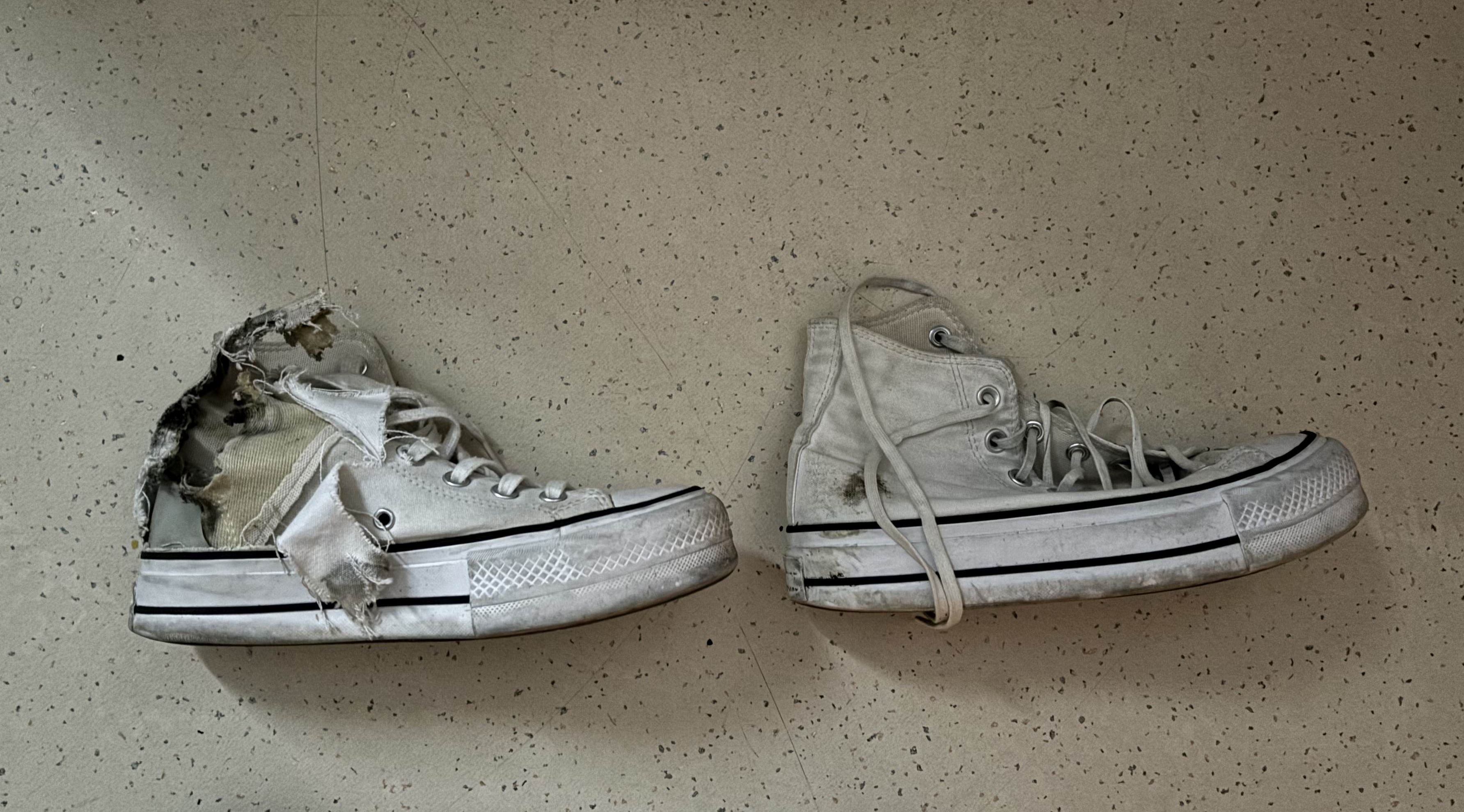 Pair of damaged sneakers on floor.