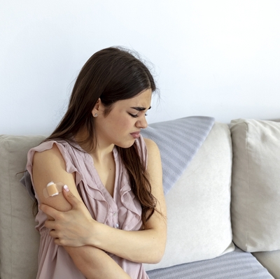 woman holding arm with post-vaccine ache