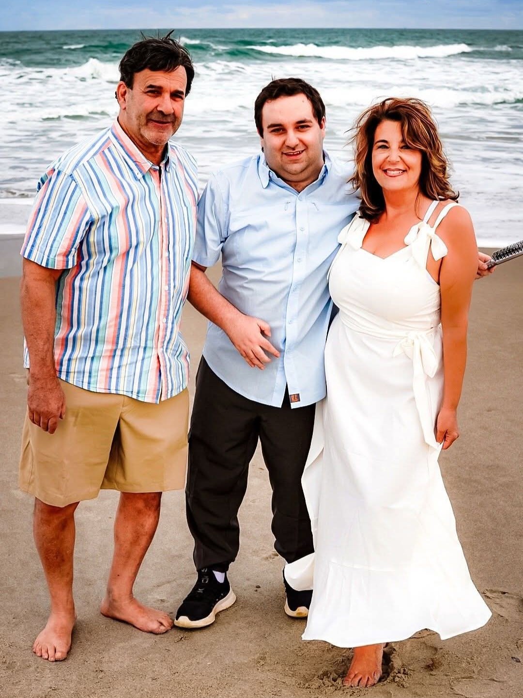 3 people stand on a beach.