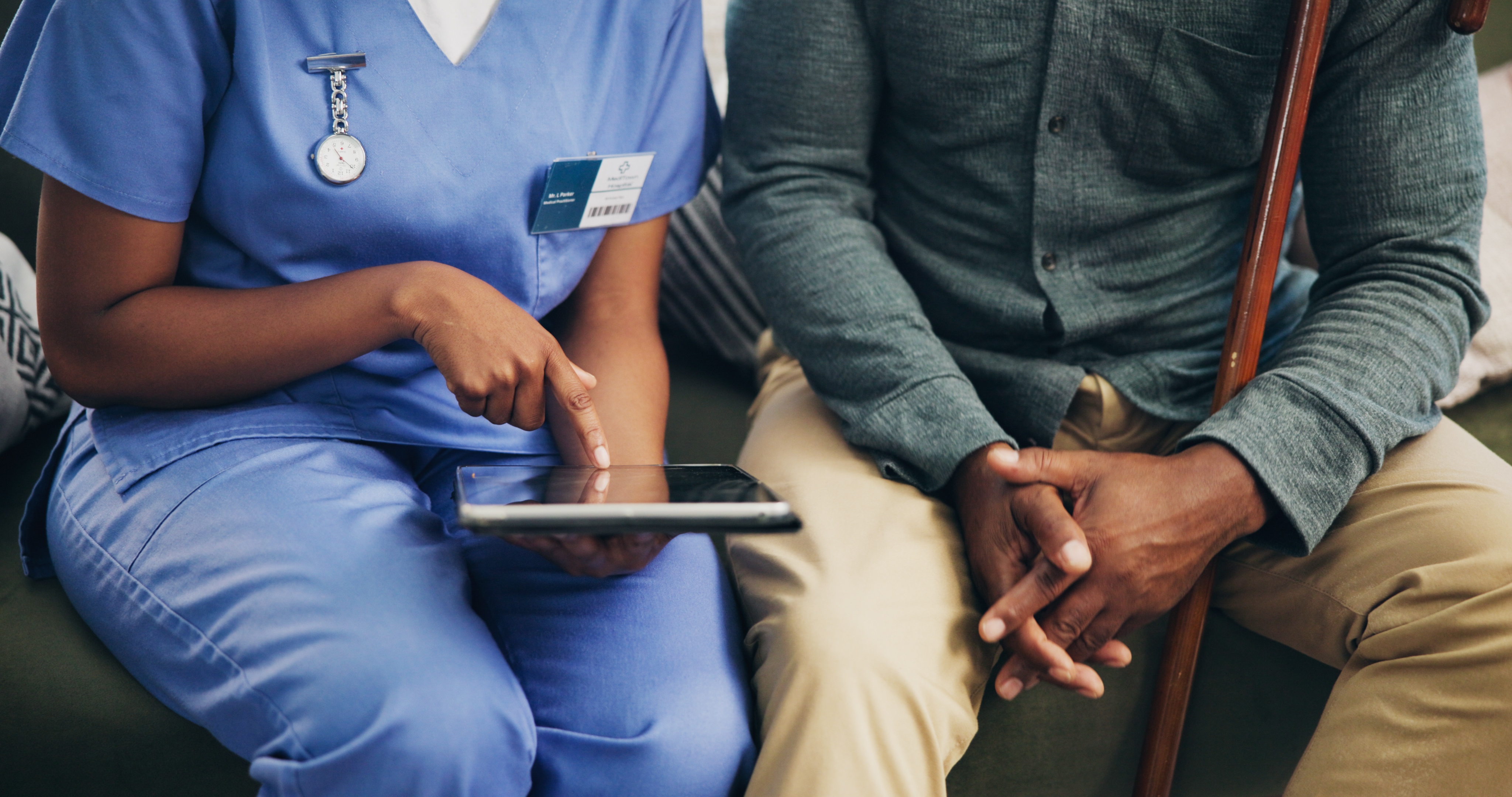 A provider sits next to a patient, checking an iPad