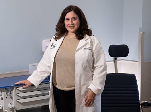 Lori Medeiros wears her white coat and poses for a photo in an exam room.