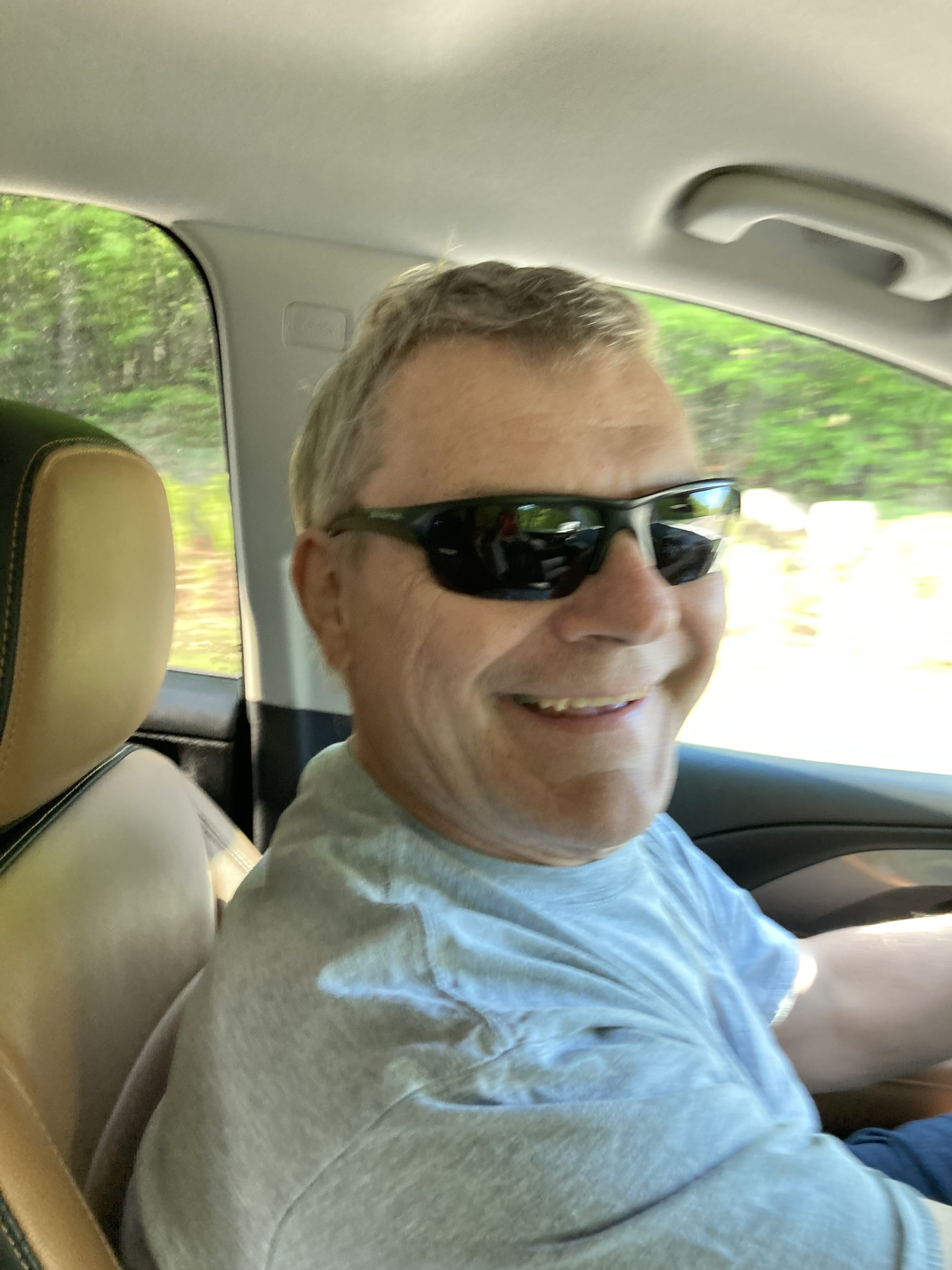 Man smiles in drivers side of car