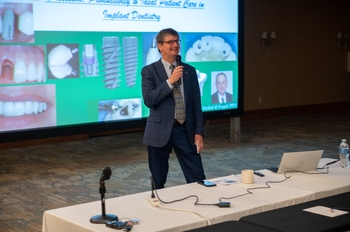 Dr. Malmstrom speaks into a microphone at a past Handelman conference.