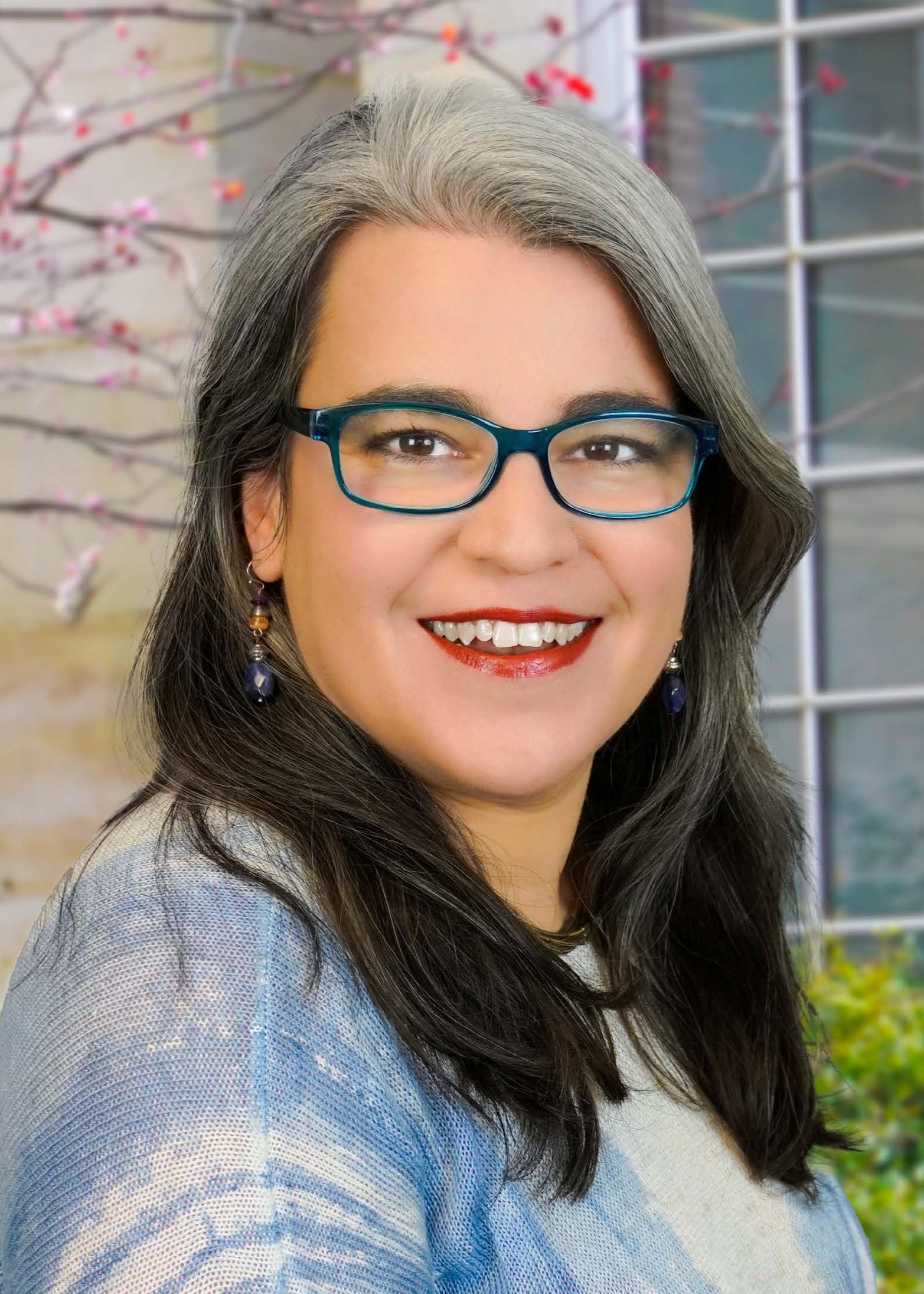 head shot of Joana, long dark hair, glasses, smiling.