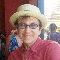 A photo of a woman wearing a red shirt and hat while sitting in a cafe.