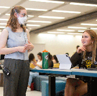 And instructor stands in front of a student in a flipped classroom. 