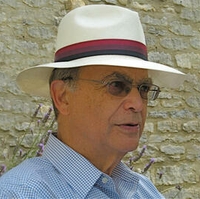 John Heilborn standing with a white, black and red striped hat wearing glasses.