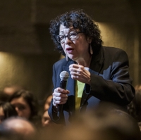 Sonia Sotomayor stands among audience members sitting in an auditorium while giving a lecture