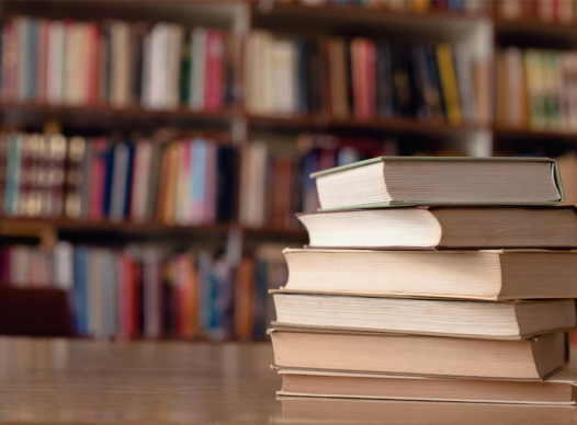 a stack of books on a table in from of a bookshelf full of books