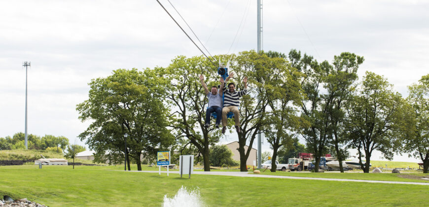 Two men coming down the zipline with their hands in the air