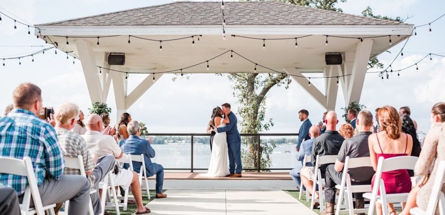 Couple at the end of the aisle getting married with their guests watching outdoors
