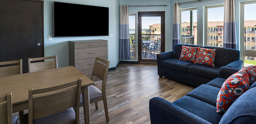 Living Area with two couches, dresser, tv, and table, with a door to the patio