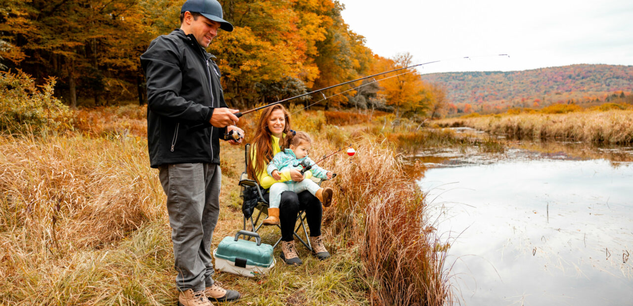 family fishing by lake in fall