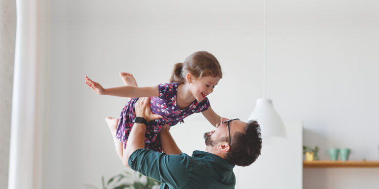 Father playing with daughter in their living room