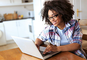 Woman using her laptop at the kitchen table