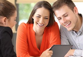 Couple talking to banker and looking at tablet