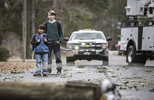 Image features two boys approaching downed power lines, following a summer storm