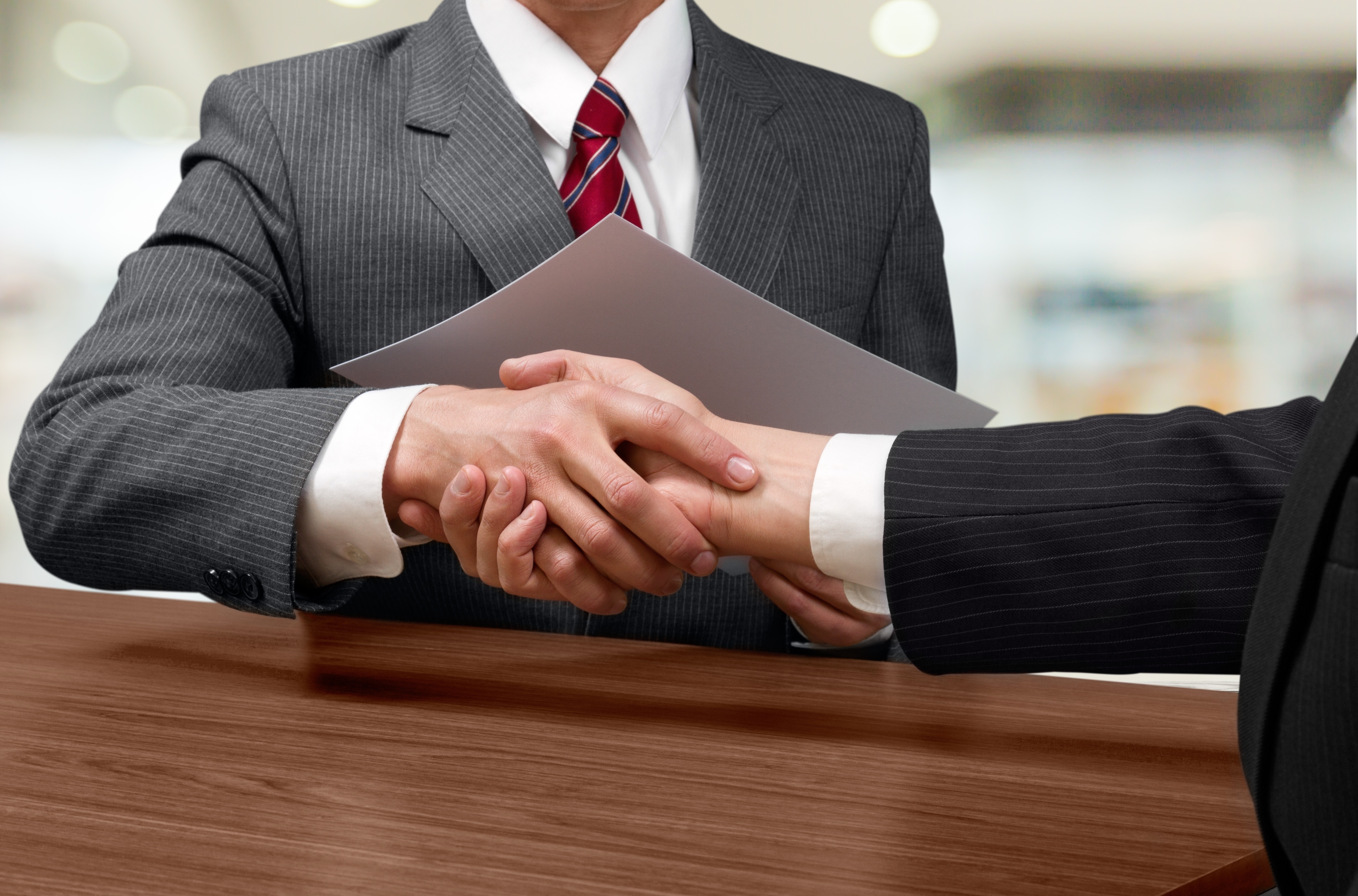businesspeople-shaking-hands-white-sitting-table.jpg