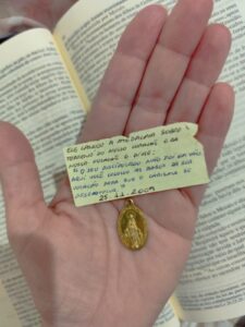 Imagem da medalha milagrosa sobre as mãos da missionária Canção Nova, Patrícia Coêlho.