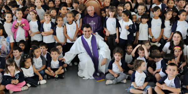 Padre Jonas Abib sentado ao centro com crianças e jovens do Instituto Canção Nova durante comemoração dos 10 anos da escola.