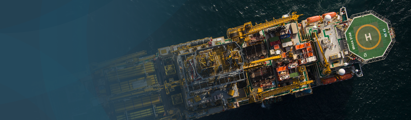 Vista aérea de plataforma de perfuração offshore com heliponto visível, destacando sua estrutura e operações em mar aberto.