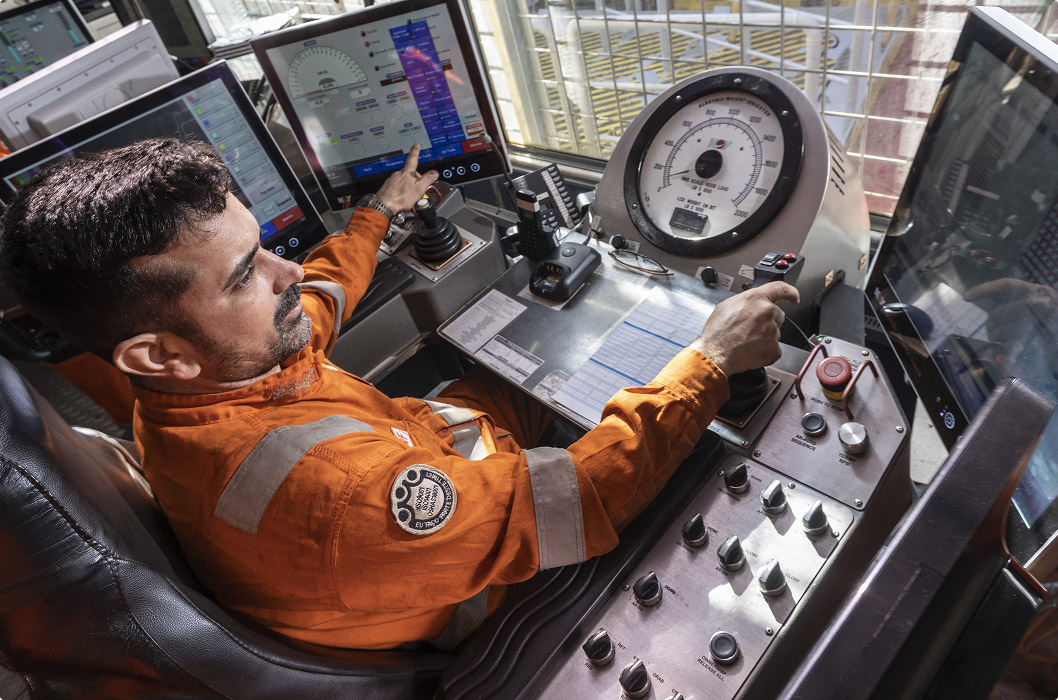 Worker operating platform controls with digital screens and control equipment