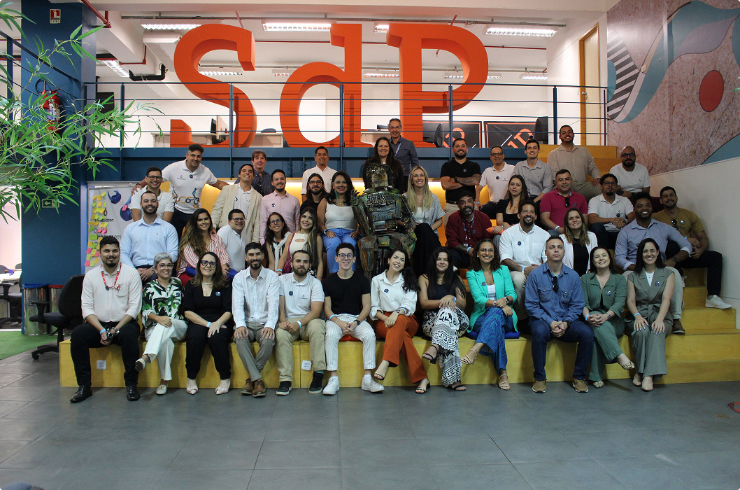 Group of employees gathered for a photo in the workplace, with large letters 'SdP' in the background.