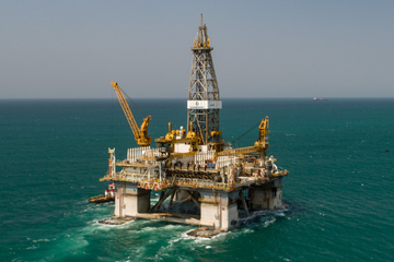 Offshore drilling platform in operation, with a prominent metallic structure, in the open sea.