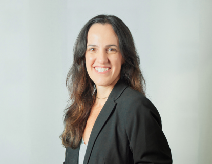 Profile photo of Monique Fares, a white woman with long dark hair, smiling and wearing a black blazer over a gray top.