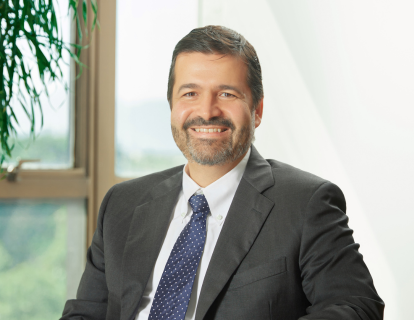 Profile photo of Rodrigo Ribeiro, a white man in a dark gray suit, white shirt and blue polka dot tie, slightly smiling.
