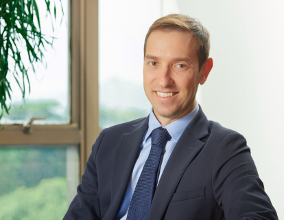Profile photo of Thiago Schimmelpfennig, a white man smiling, wearing a dark blue suit, white shirt and blue tie