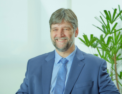 Profile photo of Rodrigo Jokubauskas, a white man with a graying beard and smiling. He wears a blue suit and a light blue tie.