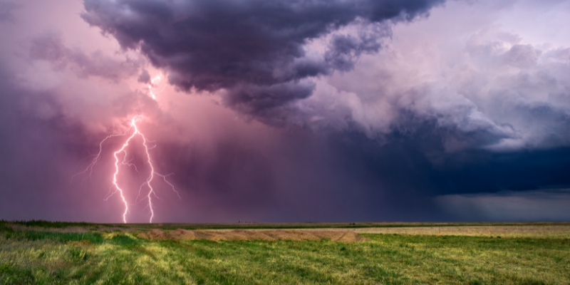 Storm over flat landscape, lightning striking the ground.