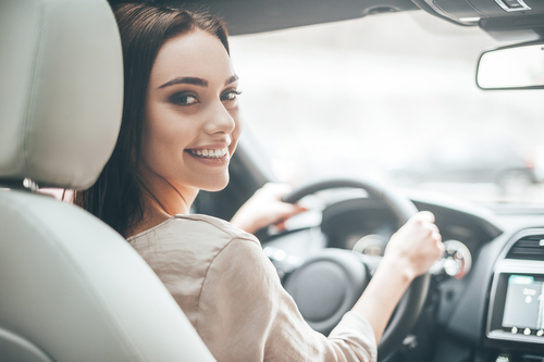young, happy, woman driving a new car