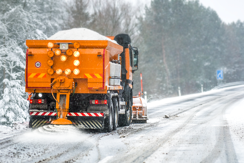 Snow plow on highway salting road.