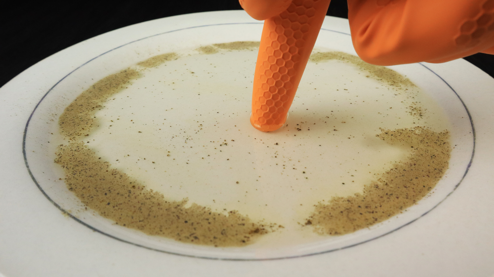 One hand touches a plate of pepper on the water.