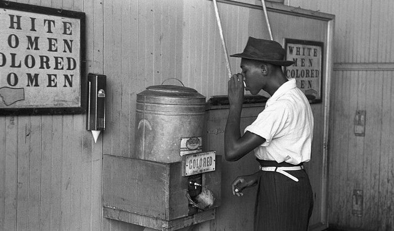  'Colored' drinking fountain from mid-20th century with an african american male drinking from it