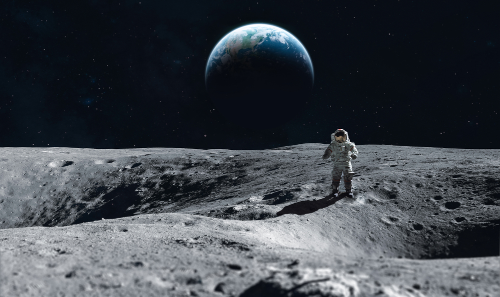 Astronaut stay on the Moon surface against Earth on the background, Exploring space and other planets 