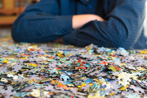 Teenager collects puzzles on coffee table. 