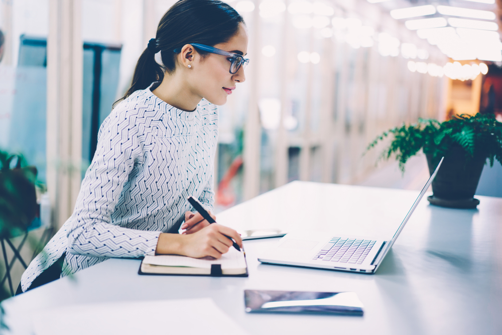 young woman, sitting at a desk and writing