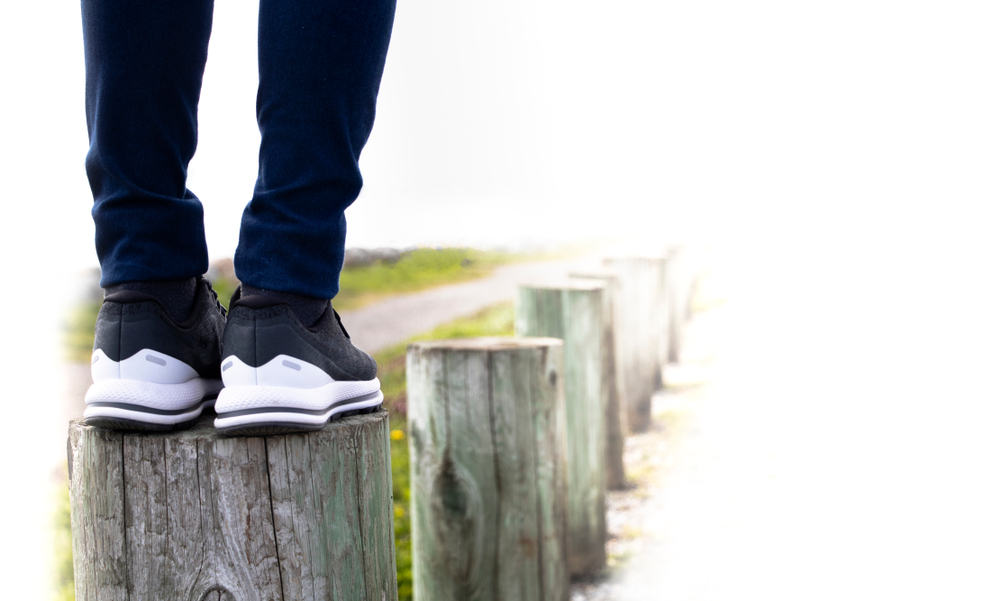 young man balancing on a post, looking to step to the next one