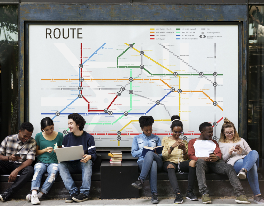 a group of young people sitting at a bus stop, with a map behind them