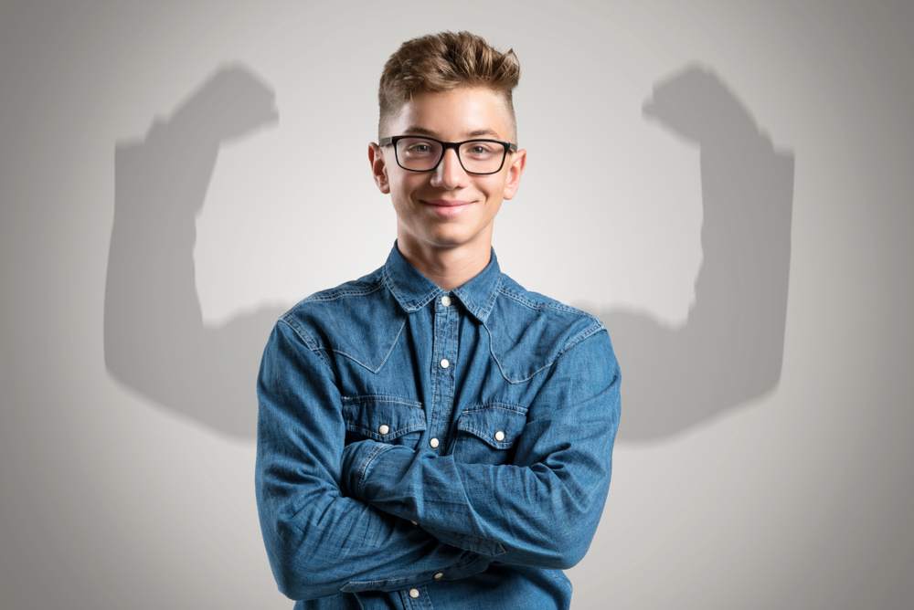 man with arms folded with shadow of arms raised in air flexing