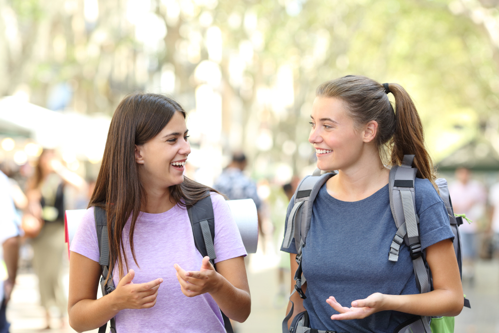 two girls walking and talking wearing backpacks