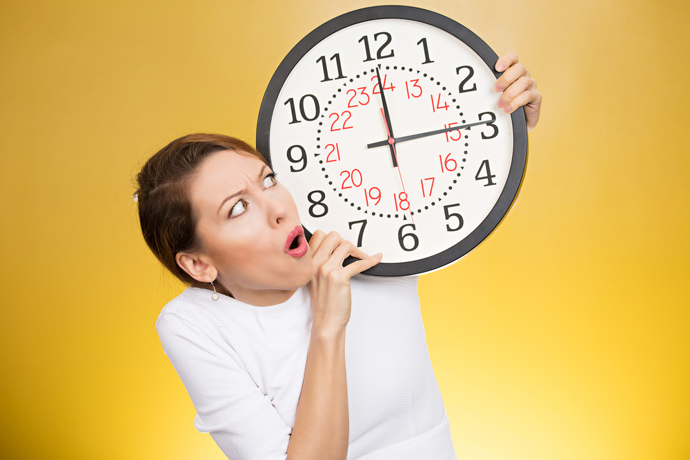 woman looking at clock reading 12:15.