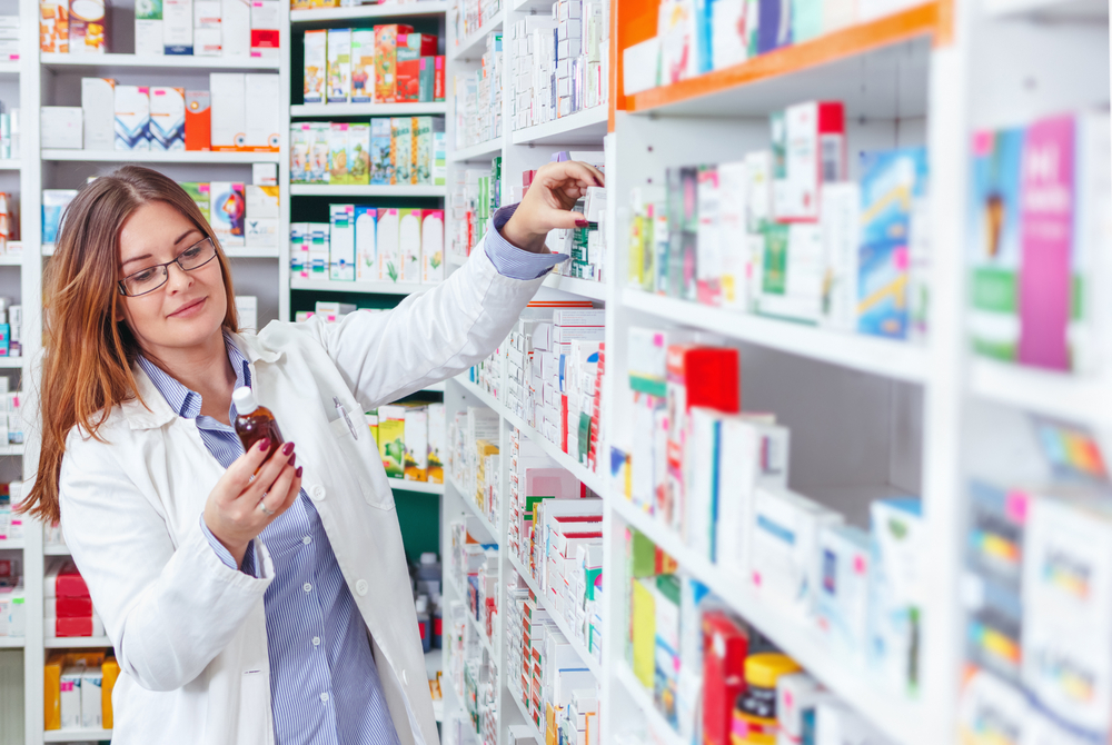 pharmacist looking at medicine and grabbing item from shelf in pharmacy