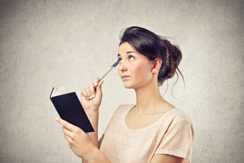 woman thinking while holding a book